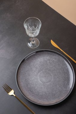 Üzerinde altın çatal bıçak takımı ve kristal cam olan gri bir tabağın üst görüntüsü. Sofistike estetik. Uzayı kopyala Zarif tablo ve modern dekorasyon kavramı