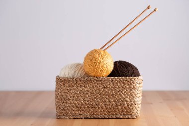 Hasır sepet iplik topları ve ahşap masa üzerinde örgü iğneleri, yatay çerçeve ve negatif boşluk. Uzayı kopyala El yapımı örgü ve rahat yaşam tarzı kavramı