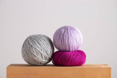 Açık ahşap yüzeyde üç iplik, fuşya ve leylak. Nötr arkaplan ile yatay minimalist kompozisyon. Uzayı kopyala El yapımı zanaat ve yavaş yaşam tarzı kavramı