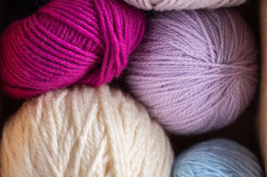 Fuşya, leylak, gri, açık mavi ve krem rengi iplik toplarıyla dolu bir kutu. Nötr arkaplan ve minimalist tarzda yatay yakın plan görüntüsü. Örgü ustalığı ve el yapımı rahat bir yaşam tarzı.