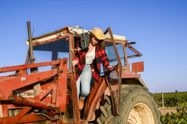 Kırmızı traktörden inen çiftçi kadın.