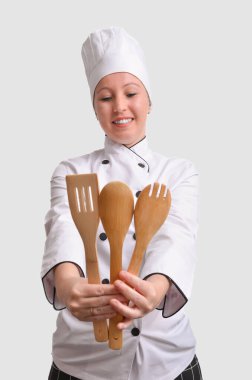 Profesyonel aşçı ahşap mutfak aletleri tutuyor, gülümsüyor, pişirmeye hazır.