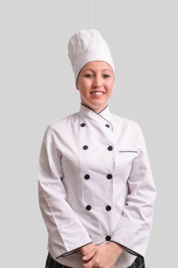 Beyaz üniforma ve şef şapkası giyerken gülümseyen kendine güvenen kadın şef aşçılık uzmanlığını ve profesyonelliği temsil ediyor.