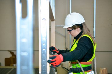 Metal çerçeveye sıva yapıştırırken ruh seviyesini kullanan kadın inşaat işçisi