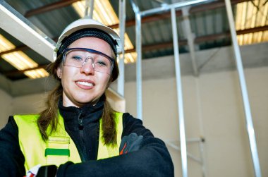 Kendine güvenen inşaat işçisi, bir binanın tavanına sıva yapıştırırken gülümsüyor.