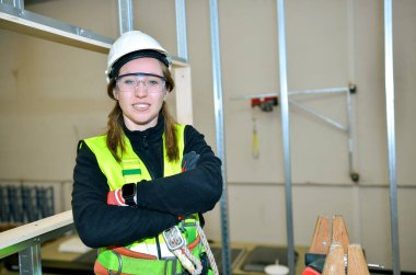 Kendine güvenen inşaat işçisi, inşaat alanında sıva tahtası monte edilirken gülümsüyor