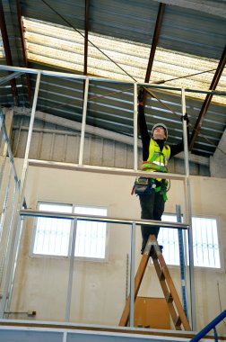 İnşaat işçisi, ahşap merdiven kullanarak, alçı kaplama tavan için metal çerçeve monte