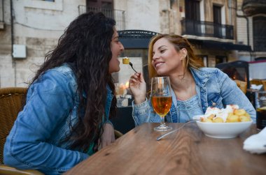 Sevgililer Günü 'nde restoranda romantik bir anı paylaşan iki kadın yemek ve içeceklerden zevk alıyor.