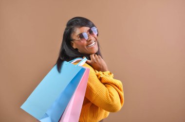 Renkli alışveriş torbaları taşıyan şık alışverişçi başarılı bir alışveriş çılgınlığından sonra gülümsüyor.