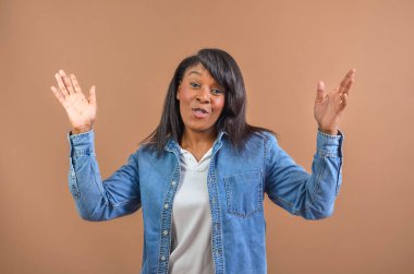 Kahverengi arka planda el kol hareketi yapan neşeli bir iş kadınının stüdyo portresi.