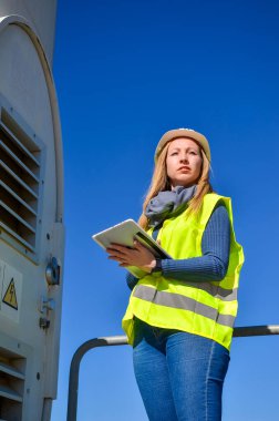 Mühendis, yenilenebilir enerji ve sürdürülebilirlik üzerine çalışan rüzgar türbini denetimi için dijital tablet kullanıyor.