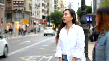 Meşgul bir şehir sokağında taksi çağıran iki bayan arkadaş.