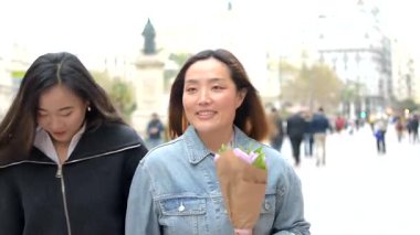 İki bayan arkadaş, hareketli bir şehir ortamında alışverişin ve manzaranın keyfini çıkarıyorlar.