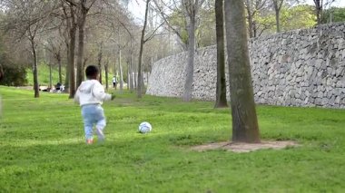 Babası kızına güzel bir parkta futbol oynamayı öğretiyor.