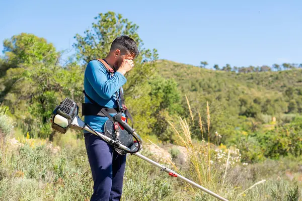 Bahçıvan alnındaki teri siliyor, dağda fırça kullanırken sıcak çarpmasından acı çekiyor.