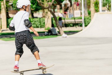 Genç kaykaycı, kaykay parkında koruyucu giysiler giyerek pratik yapıyor.