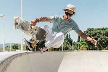 Genç adam kaykay yapıyor ve kaykay pistinde bir numara yapıyor.