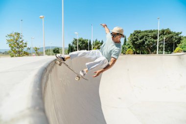 Kaykay yapan genç bir adam, kaykay pistinde bir numara yapıyor.