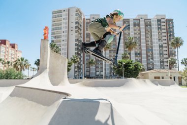 Gençler kaykay parkında motosiklet numaraları yapıyor, yükseğe zıplıyor ve yeteneklerini sergiliyor.