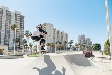 Şehirdeki bir kaykay parkında kaykayla atlayan genç bir kaykaycı.