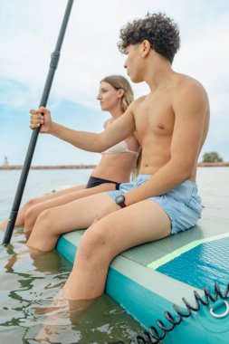 Çift kürek tahtasında dinleniyor, suda yaz gününün tadını çıkarıyor.