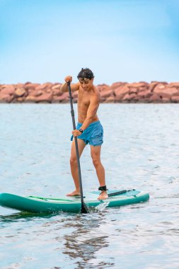 Gençler güneşli bir günde açık denizde sörf yapmaya hazırlanıyor.