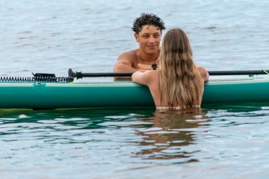 Genç çift kürek çekmeye ara verip okyanusun huzurunun tadını çıkarıyor.