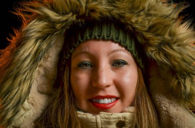 Kürklü kışlık ceket giyen gülümseyen bir kadının yakın plan portresi.