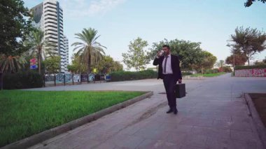 Kendine güveni tam bir işadamı. Çantasını taşır, şehir parkında yürür ve yeniden kullanılabilir bir bardaktan içer.