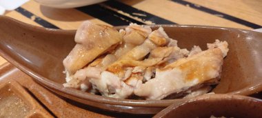 Nasi Hainan ya da Hainan tavuğunun pek çok kısmı ahşap masada tofu çorbası, domates, salatalık ve salatalık ile servis edilir. Hainanese tavuğu pilavı, Güney Çin 'in Hainan kentinden gelen haşlanmış tavuk ve baharatlı pirinçtir..