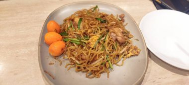 Pancit Canton, Lo Mein veya un çubuğu olarak bilinen bir erişte türüdür. Bu yemek genellikle doğum günlerinde ve uzun yaşamı sembolize eden özel günlerde servis edilir. Tahta masada.