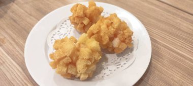 Beyaz tabakta kızarmış gamsum ve ahşap masa.