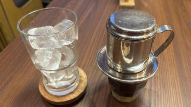 Bir bardak buzlu su ve tahta masada bir kaşık.