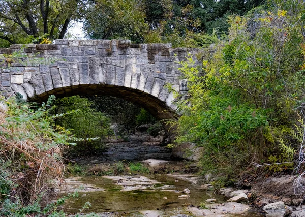 Old arched foot bridge over creek, in Blanco, TX.