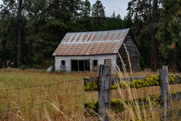 農民の古い塀の背後にある放棄された木造の学校の建物 — ストック写真