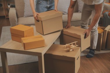 Güzel, genç ve aşık bir çift yeni dairelerine taşınırken karton kutulardan bir şeyler çıkarırken eğleniyorlar.
