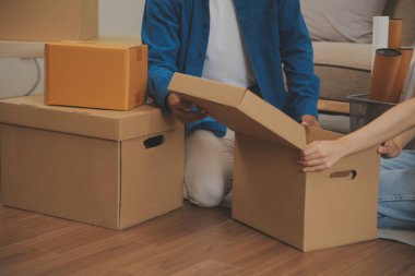 Güzel, genç ve aşık bir çift yeni dairelerine taşınırken karton kutulardan bir şeyler çıkarırken eğleniyorlar.