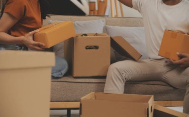 Güzel, genç ve aşık bir çift yeni dairelerine taşınırken karton kutulardan bir şeyler çıkarırken eğleniyorlar.