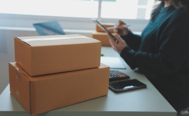 Startup SME small business entrepreneur of freelance Asian woman using a laptop with box Cheerful success Asian woman her hand lifts up online marketing packaging box and delivery SME idea concept