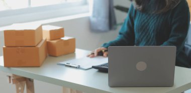 Startup SME small business entrepreneur of freelance Asian woman using a laptop with box Cheerful success Asian woman her hand lifts up online marketing packaging box and delivery SME idea concept