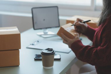 Startup SME small business entrepreneur of freelance Asian woman using a laptop with box Cheerful success Asian woman her hand lifts up online marketing packaging box and delivery SME idea concept