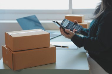 Startup SME small business entrepreneur of freelance Asian woman using a laptop with box Cheerful success Asian woman her hand lifts up online marketing packaging box and delivery SME idea concept