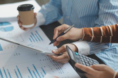 Finansal analistler, şirketlerin başarılı takım çalışmalarının sonuçlarını gösteren bir toplantıda bir dijital tablet planlama yatırım projesinin ticari mali raporlarını analiz ediyorlar..