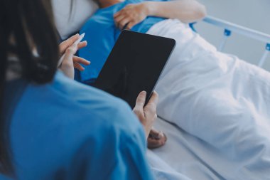 Asyalı kadın doktorlar hastanın elini tutarlar ve hasta sağlığını kontrol ederken ona tıbbi tavsiyelerde bulunurlar. Bakım ve şefkat kavramı, doğum öncesi bakım, kürtaj tehdidi