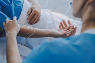 Asyalı kadın doktorlar hastanın elini tutarlar ve hasta sağlığını kontrol ederken ona tıbbi tavsiyelerde bulunurlar. Bakım ve şefkat kavramı, doğum öncesi bakım, kürtaj tehdidi