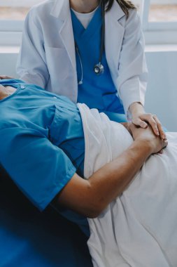 Asyalı kadın doktorlar hastanın elini tutarlar ve hasta sağlığını kontrol ederken ona tıbbi tavsiyelerde bulunurlar. Bakım ve şefkat kavramı, doğum öncesi bakım, kürtaj tehdidi