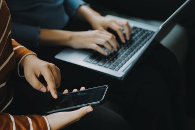 Dışarıda oturup dizüstü bilgisayar kullanan güzel bir kadın. Kadın ve arkadaşı yeni teknolojiyle eğleniyor ve açık havada online alışveriş yapıyorlar..
