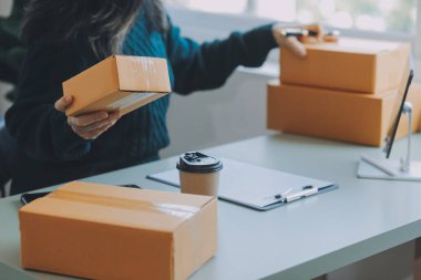 Startup SME small business entrepreneur of freelance Asian woman using a laptop with box Cheerful success Asian woman her hand lifts up online marketing packaging box and delivery SME idea concept