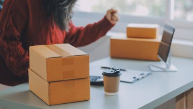 Startup SME small business entrepreneur of freelance Asian woman using a laptop with box Cheerful success Asian woman her hand lifts up online marketing packaging box and delivery SME idea concept