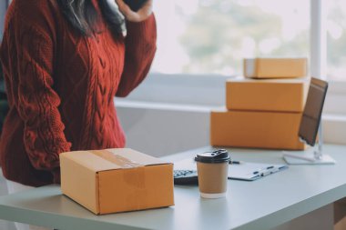 Startup SME small business entrepreneur of freelance Asian woman using a laptop with box Cheerful success Asian woman her hand lifts up online marketing packaging box and delivery SME idea concept